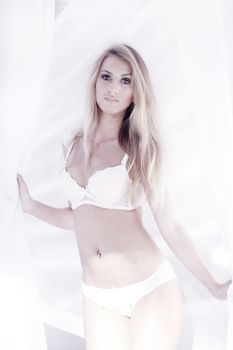 Beautiful female model wearing lingerie over waving white fabric background