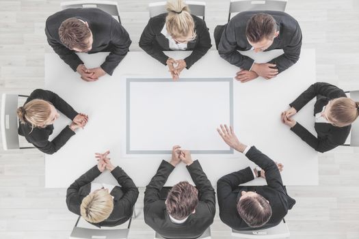 Business people sitting around blank frame on table, business man pointing to blank copy space in the middle
