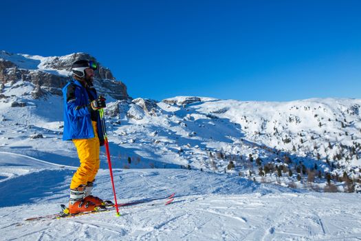 Alpine skier stand on slope in winter mountains Dolomities Italy in beautiful alps Cortina d'Ampezzo Cinque torri mountain peaks famous landscape skiing resort area