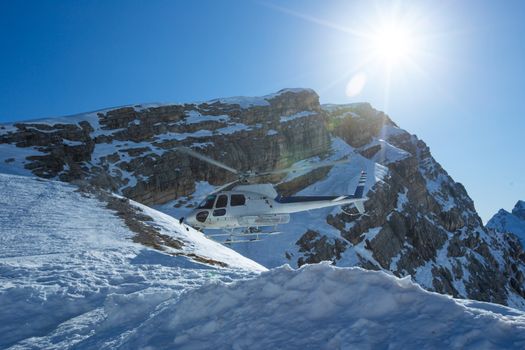 Heli Skiing Helicopter is landing on a ski slope in Dolomities Dolomiti Italy alps winter mountains and ski slope Cortina d'Ampezzo Cinque torri mountain peaks skiing resort area