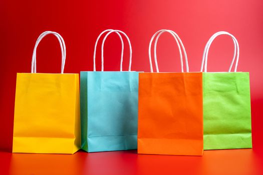 Four colorful gift or shopping bags isolated on red background