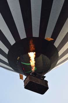 Hot-air balloon taking off with fire flame background blue sky