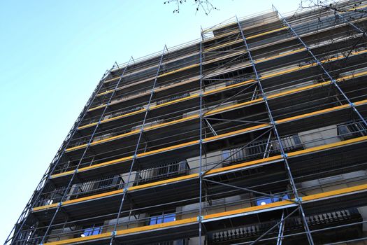 Yellow scaffolding of a building under restoration on a clear sunny day in Barcelona