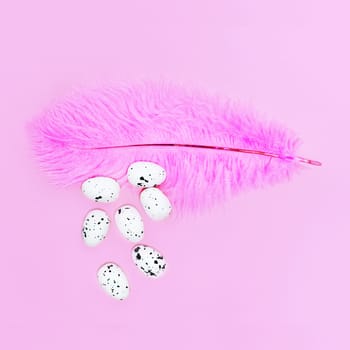 Eggs on a pink feather on a pink background. Easter concept