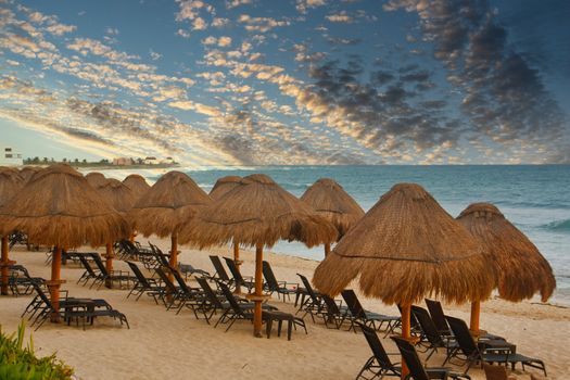 A tropical beach with chaise lounges and straw thatched umbrellas