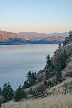Scenery overview of Okanagan lake on summer sunset. Okanagan lake view with mountains on the background