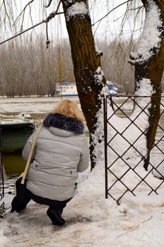 Winter with ice-cold water on the Borcea arm at the end of winter.
The blonde woman looks at the beauty of nature through the willows window