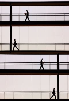 Silhouette view of businessmen in a modern office building interior with panoramic windows.