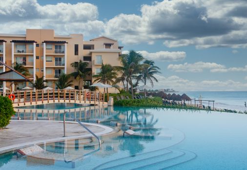 A calm resort swimming pool by a beach in the early morning