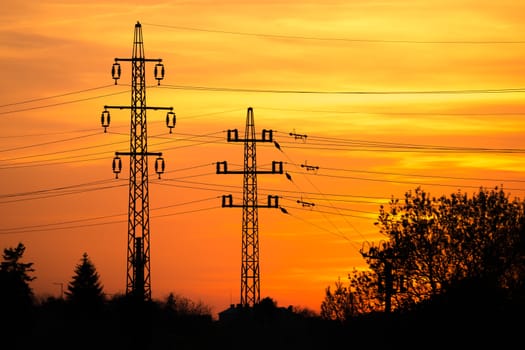 View at a Silhouette of Electric Lines and Column Pillar during Sunset with Clouds on the Sky.Beautiful sunset Nature . Beautiful rural landscape with electric pillars .