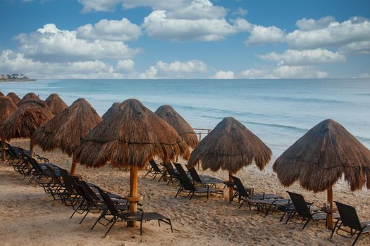 Rows of straw thatch umbrellas and chaise chairs on beach