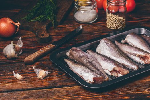 Hake carcasses on baking sheet with vegetables and spices