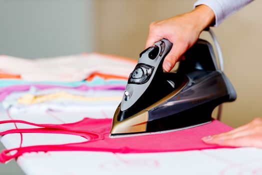 Female hand ironing clothes on ironing board