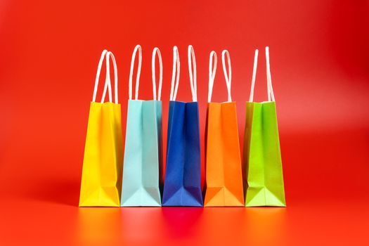 Five colorful gift or shopping bags isolated on red background