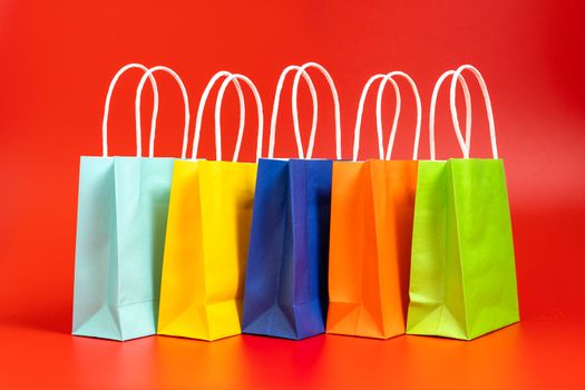 Five colorful gift or shopping bags isolated on red background
