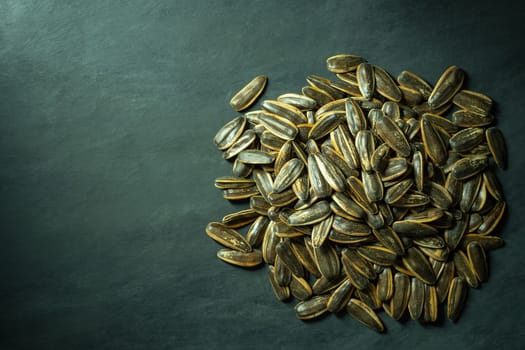 Sunflower seeds heap on black cement floor. Top view and copy space for text. Concept of agriculture and organic farm.