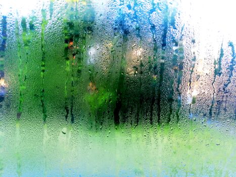 raindrops slide down the window glass, forming abstract figures