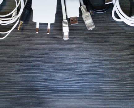 USB cables, charging cables, as well as many other connecting cables, are placed on a wooden table.