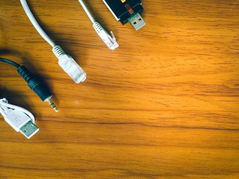 USB cables, charging cables, as well as many other connecting cables, are placed on a wooden table.