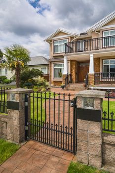 Luxury residential house with palm tree on the front yard behind metal fence