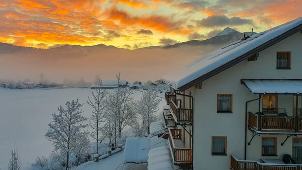Sunrise over Snowy Mountains With German looking Building against a red and Yellow Sky