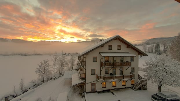 Sunrise over Snowy Mountains With German looking Building against a red and Yellow Sky