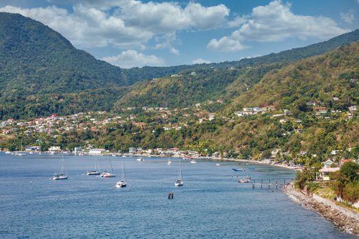 Many white boats moored in a blue bay off the coast of Dominica near Rosseau