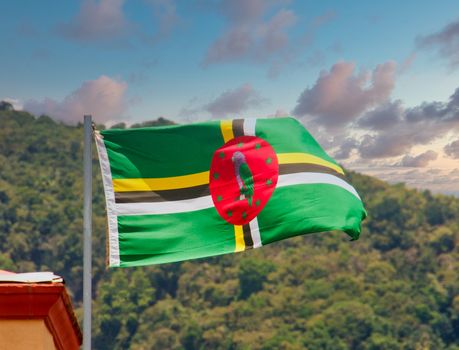 Flag of Dominica Blowing Against background of hills and clouds