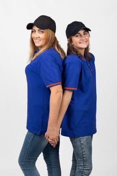 Two different-aged girls of European appearance in the same clothes stand with their backs to each other