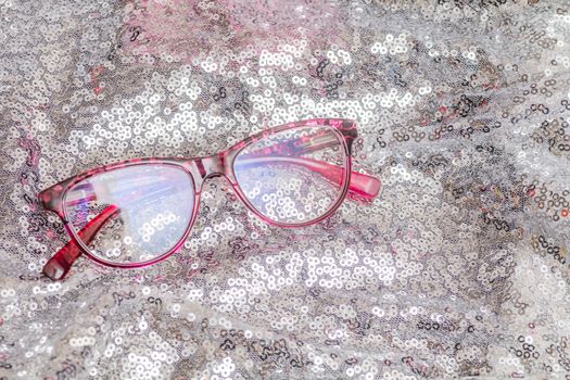 Pair of cheap reading glasses with pink frame on silver backround