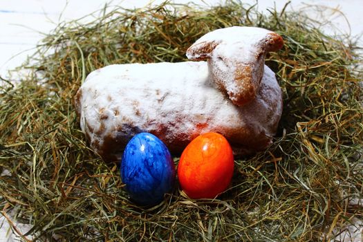 The pictureshows an easter lamb in straw and easter eggs