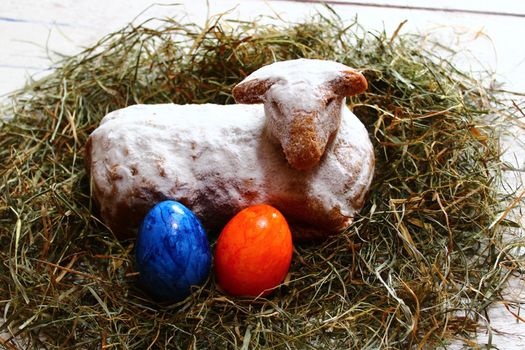 The picture shows an easter lamb in straw and easter eggs