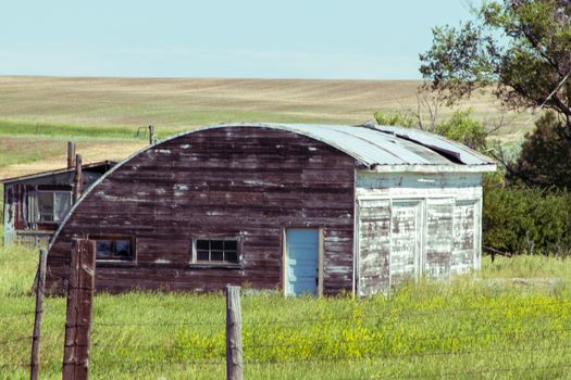 A old abandon house with a fence in a grassy field. High quality photo