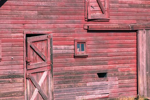 Close-up of the front of an old abandoned red barn with door and windows 
