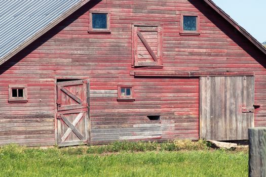 A large old abandon barn with grass in front of a house. High quality photo