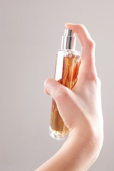 hands ready to spray perfume with grey background