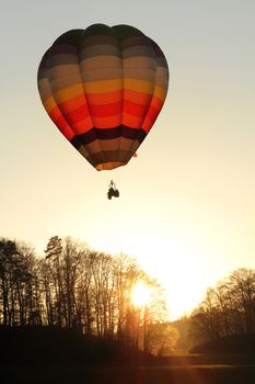 Hot air balloon above forrest and sunset