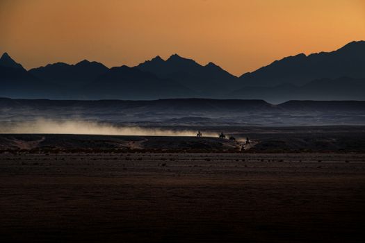 quads in dessert during twilight with dust trail