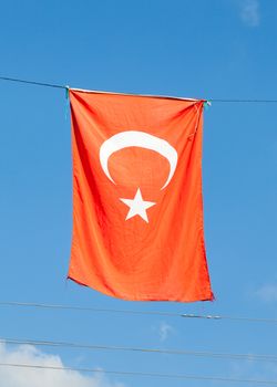 The Turkish flag hangs vertically against a blue sky.