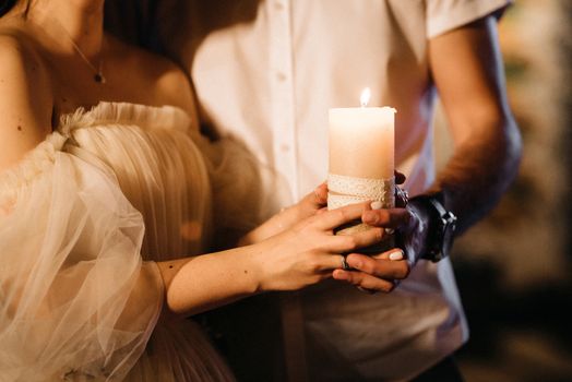 the bride and groom held candle in hands
