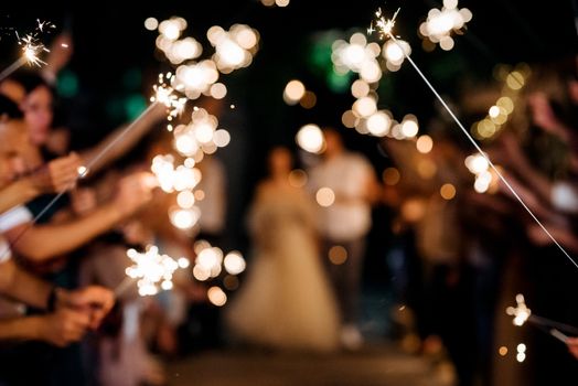 sparklers at the wedding, a couple of newlyweds on the background