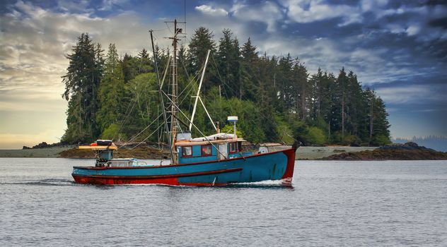 A blue shrimp boat trolling the grey waters of Alaska