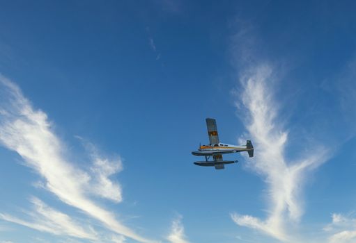 A yellow and white seaplane shot from below