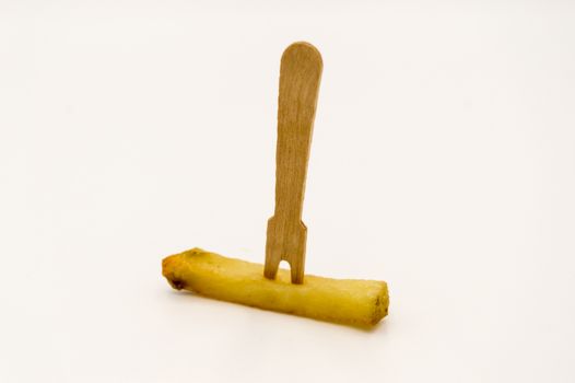 Wooden fries fork on a baked french fries on a white background