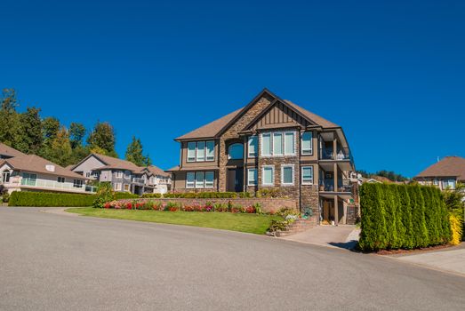 Luxury house in center of the neighborhood with landscaped front yard and blue sky background