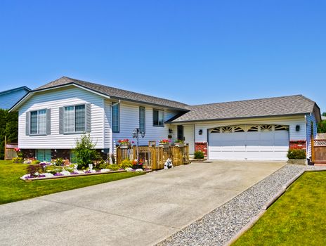 Average residential house with wide garage and concrete driveway on blue sky background