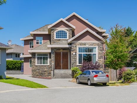 Luxury family house with a car parked on concrete driveway. Residential house on sunny day on blue sky background