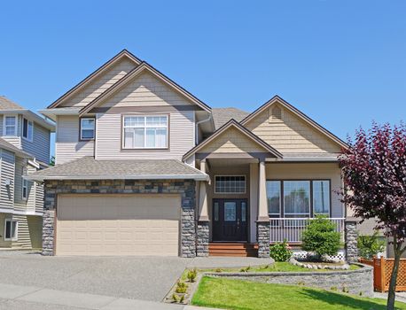 Luxury residential house with wide garage and concrete driveway on blue sky background