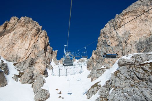 Ski lift chairs on bright winter day Dolomities Dolomiti Italy in wintertime beautiful alps mountains and ski slope Cortina d'Ampezzo Cinque torri mountain peaks famous landscape skiing resort area