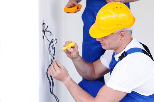 Electrician put electrical wires for wall socket using screw driver
